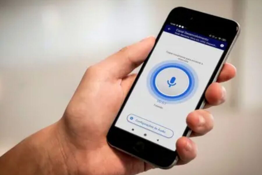 uma mão segurando celular gravando áudio