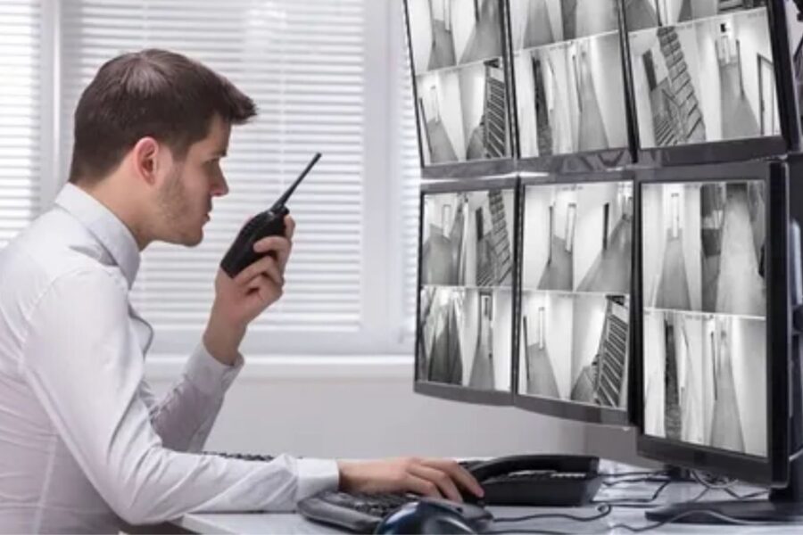 segurança monitorando câmeras de segurança e falando no rádio comunicador