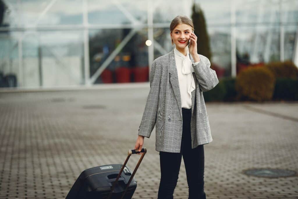 mulher com mala de viagem usa mobile empresarial