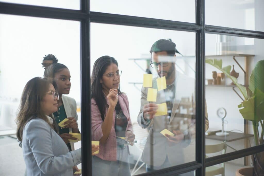 mulheres observam post its colados em janelas, participam de uma dinâmica de produtividade